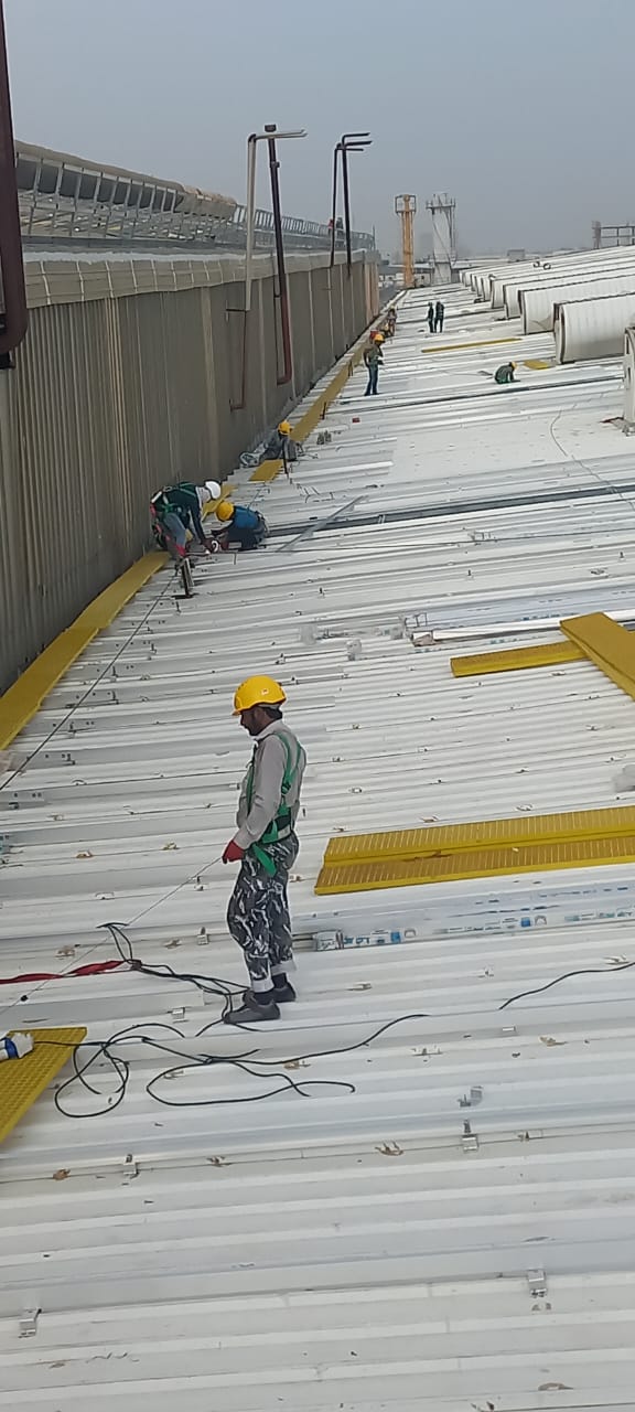 Waterproofing team working across a large industrial metal roof