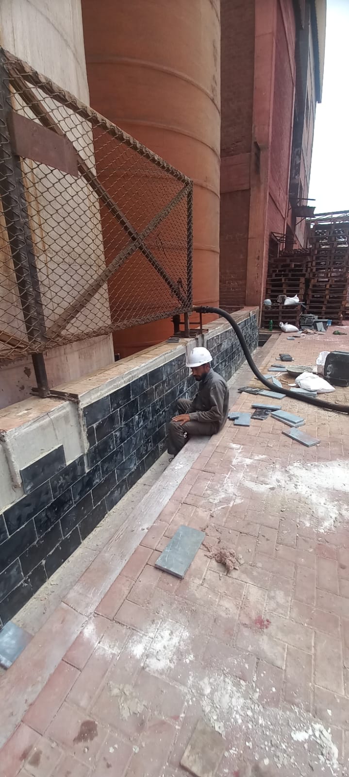 Acid-proof tiles installed along an industrial tank foundation